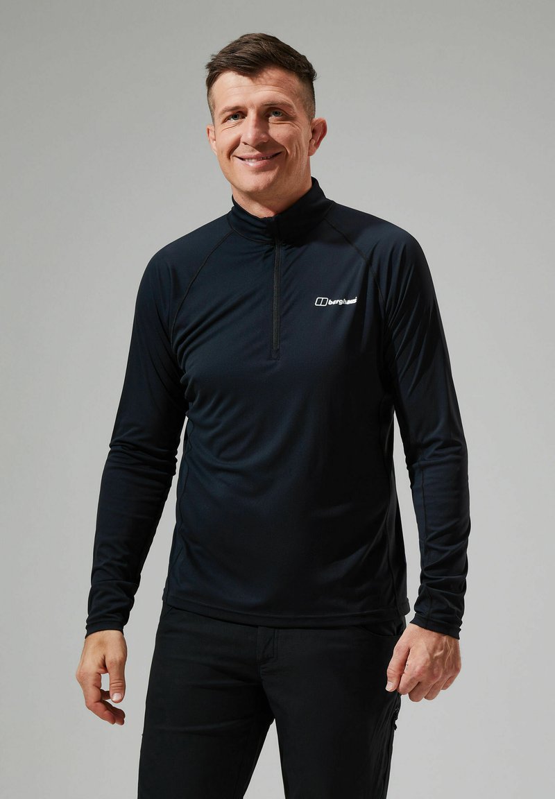 Langsleeve, strakke zwarte performance top met een kwart-rits kraag en logo op de borst. Gemaakt van lichtgewicht, gladde stof.