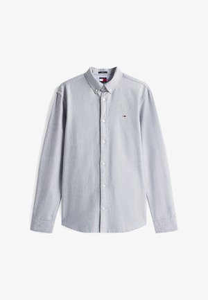 Svetlo siva srajca z dolgimi rokavi in gumbi, z majhnim rdeče-belo-modrim logotipom na levi strani prsi in ovratnikom z gumbi.