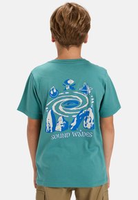 Turquoise cotton t-shirt featuring a blue graphic of abstract shapes and mountains on the back, with text "SOUND WAVES" at the bottom.