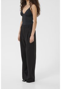 Débardeur noir à fines bretelles associé à un pantalon noir taille haute à jambes larges. Tissu lisse, coupe ajustée, plis subtils, style minimaliste.