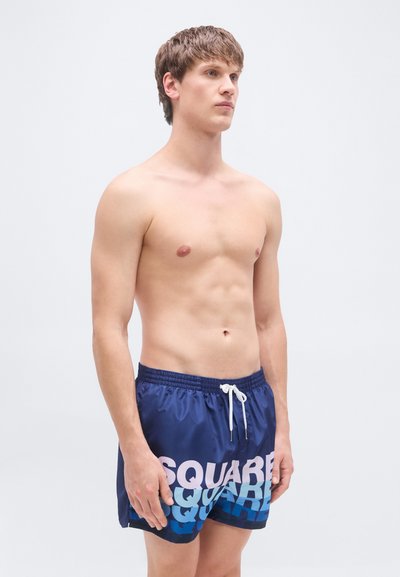 Μπλε ναυτικές βερμούδες κολύμβησης με διαβαθμισμένο σχεδιασμό κειμένου σε ροζ και μπλε, ελαστική μέση με λευκό κορδόνι και ελαφριά, λεία υφή.