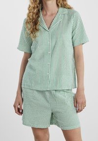 Zielono-białe, w paski, krótkie piżamy z krótkim rękawem, z koszulą zapinaną na guziki i pasującymi szortami, wykonane z lekkiego materiału o miękkiej teksturze.