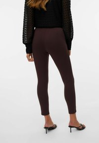 Bordeaux leggings met een soepele textuur, voorzien van een aansluitend ontwerp en een enkel-lengte snit, gecombineerd met zwarte hoge hakken sandaaltjes.