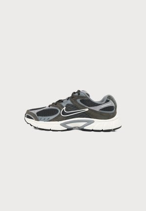 Mørkegrå og sort Nike løbesko med hvid sål og swoosh-logo, vist fra siden på en lysegrå baggrund.
