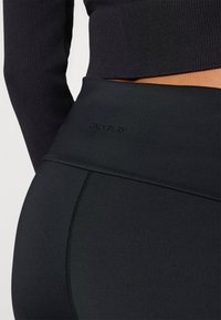 Black high-waisted leggings made from stretch fabric, featuring a seamless design and embossed "ONLY PLAY" logo on the waistband.