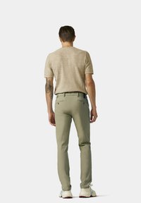 Beige Kurzarmhemd, Slim-Fit olivgrüne Hose und weiße Sneakers mit bunten Akzenten. Fokussiert auf modernes, lässiges Mode-Design.