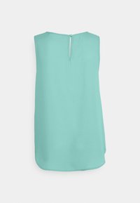 Uma blusa sem mangas na cor turquesa suave, com um fecho nas costas em forma de chave e um tecido liso e fluido com uma bainha arredondada.