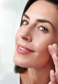 Close-up of a woman’s face with smooth, light skin. She has full lips with a natural pink shade, expressive eyes, and neatly groomed eyebrows.