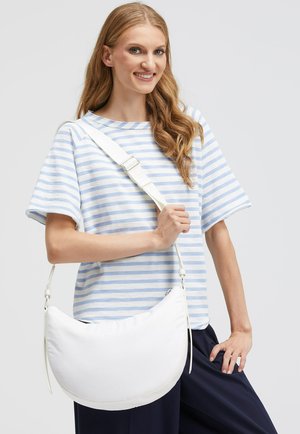 Weißer Hobo-Bag mit glatter Textur, geschwungener Form und verstellbarem Tragegurt. Kombiniert mit einem blau gestreiften Hemd und lockeren, dunklen Hosen.