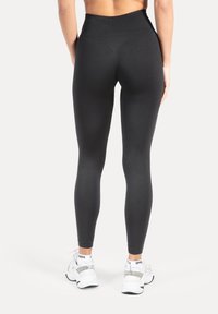 Leggings neri a vita alta realizzati in tessuto elastico e liscio con un design elegante, caratterizzati da una vestibilità aderente e senza ornamenti visibili.