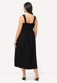 Musta maksimekko leveillä olkaimilla, räävityllä bodice:lla ja valuvalla hameella. Pehmeä kangas, polven pituinen, minimaalinen ompelutaito, käytetään korkokenkien kanssa.