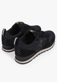 Zwarte sportschoenen met een bovenwerk van suede, vetersluiting, rubberen zool en een doodskoplogo aan de zijkant met een contrasterende witte accento.