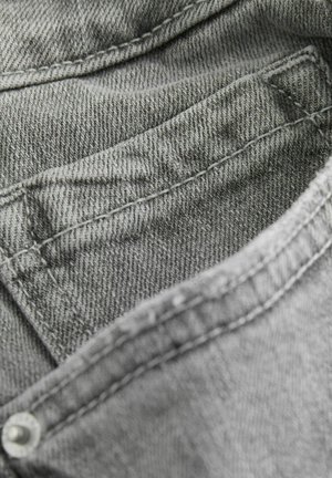 Tissu denim gris avec un motif en chevrons, présentant une poche visible, des coutures méticuleuses et une texture douce.