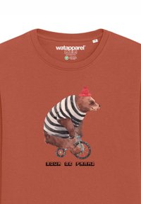 T-shirt couleur rouille avec un graphisme d'un ours à bicyclette, portant une chemise rayée noir et blanc et un bonnet rouge, avec le texte "Tour de Franz".