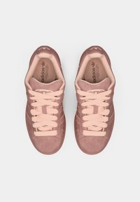 Tenisové topánky z ružového semišu s ladiacimi šnúrkami, polstrovaným golierom a výrazným dizajnom troch pruhov na bokoch. Ploché gumové podrážky.