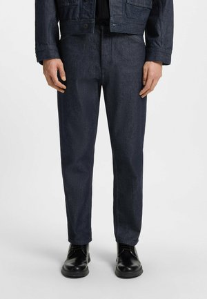 Donkerdenim broek met een rechte pasvorm, voorzien van subtiele textuur, standaard zakken en gecombineerd met zwarte schoenen.