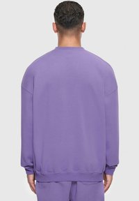 Lila Sweatshirt mit lockerer Passform, gerippten Bündchen und Kragen. Glatte Textur in einfarbiger Ausführung ohne sichtbare Muster oder Logos.