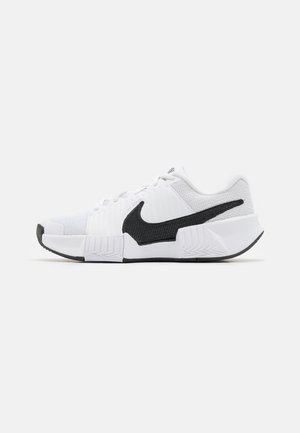 Weiße Sportschuhe mit schwarzen Akzenten, ausgestattet mit einem strukturierten Mesh-Obermaterial, gepolsterter Kragen und Gummisohle mit Zickzackmuster.