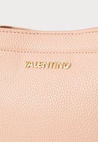 Ljust rosa texturerad läderväska med guld "VALENTINO"-logotyp, som är framträdande högst upp, med detaljerad sömnad längs sömmen.