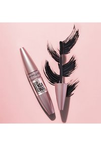 Mascara Maybelline Lash Sensational con un tubetto metallico rosa, accompagnato da un applicatore nero accanto a tratti di mascara nero intenso su uno sfondo rosa.
