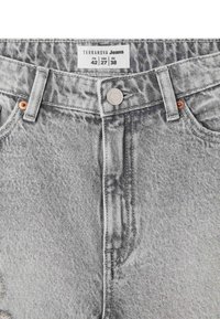 Jeans in denim grigio con una texture liscia, caratterizzati da un bottone argento e rivetti in rame. L'etichetta riporta la scritta "Terranova Jeans" con informazioni sulla taglia.