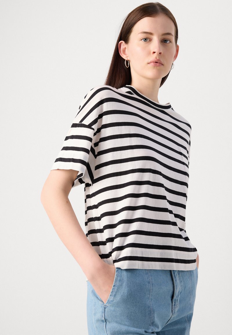 Schwarz-weiß gestreift Baumwoll-T-Shirt mit lässiger Passform, Rundhalsausschnitt, kurzen Ärmeln und einer kleinen Brusttasche. Kombination mit hellblauem Denim.