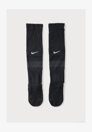 Een paar zwarte kniehoge Nike sportsokken met een wit Nike swoosh-logo vlak bij de bovenkant en een subtiel donkere band onder het logo.
