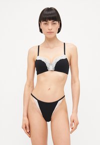 Zwart lingeriesetje met kantafwerking. De bralette heeft verstelbare bandjes en een draadframe. De string heeft kantaccenten aan de zijkanten.