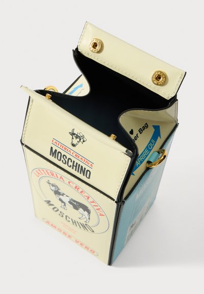 Kartiņa formas rokassoma ar krēmkrāsas un zilu mākslīgo ādu. Aprīkota ar zelta toņu metāla daļām, drukātām grafikām un atvērta augšdaļa ar spiedpogu aizdarēm.