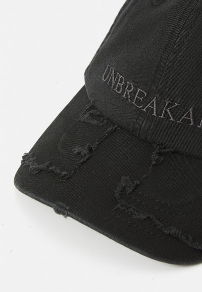 Black distressed baseball cap with frayed fabric details and "UNBREAKABLE" embroidered across the front panel in matching black thread.