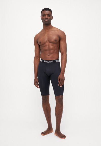 Shorts de sport noirs avec une coupe ajustée, dotés d'une ceinture de marque. Texture lisse, sans motifs, atteignant juste au-dessus du genou.