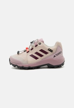 Zapato de senderismo rosa claro y morado con suela negra, tres rayas oscuras en el lateral, sistema de cordones rápido y etiqueta Gore-Tex.