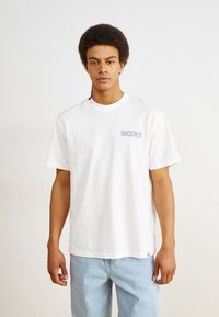 White cotton t-shirt featuring short sleeves, a round neckline, and a small printed "DICKIES" logo on the left chest.
