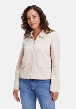 Lichtbeige suède jas met een kraag, ritssluiting aan de voorkant en twee klepzakken. Glad textuur en op maat gemaakt ontwerp met lange mouwen.