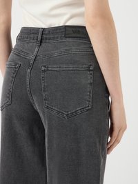 Jeans de mezclilla gris oscuro con corte recto, que cuentan con un parche de logo en la parte trasera de la cintura y dos bolsillos traseros con un diseño puntiagudo.