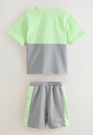 Ensemble de sport gris et vert clair comprenant un T-shirt à manches courtes avec un design bicolore et un short avec une taille élastique et des accents latéraux.