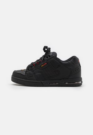 Czarny niski sneaker z wyściełanym kołnierzem, czerwonymi akcentami na oczkach na sznurówki, widoczną podeszwą z poduszką powietrzną oraz metką marki Globe po boku.