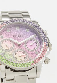 Hõbedane kell, millel on gradient glitter-eni dial, roosa ja rohelise aladial ja bezel, millel on kaunistustena roosa, roheline ja lilla kivid.