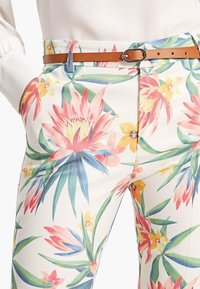 Bloemenpatroon broeken van lichte stof met levendige roze, gele en groene kleuren, voorzien van een bruine riem en zilveren gesp.