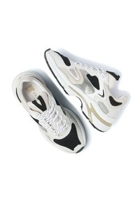 Baskets avec un mélange de matériaux blancs, noirs et beiges, dotées d'accents en maille, de lacets ronds et d'une semelle en caoutchouc épaisse.