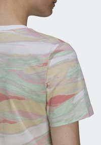 Bavlněné tričko s multikolorovým pastelovým abstraktním vzorem v zelené, růžové a žluté barvě, s kulatým výstřihem a krátkými rukávy.
