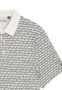 Vit polo-t-shirt med en texturerad svart mönster av tårformade former, med en klassisk krage och tre knappar.