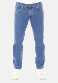 Jeans de mezclilla azul claro con corte recto, cinco bolsillos, cierre de botón y costuras en color contrastante, combinados con zapatillas blancas.