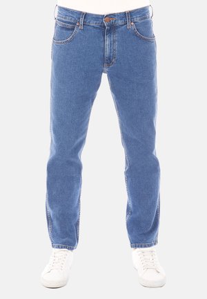 Jeans in denim blu chiaro con taglio dritto, cinque tasche, chiusura con bottone e cuciture in contrasto, abbinati a sneakers bianche.
