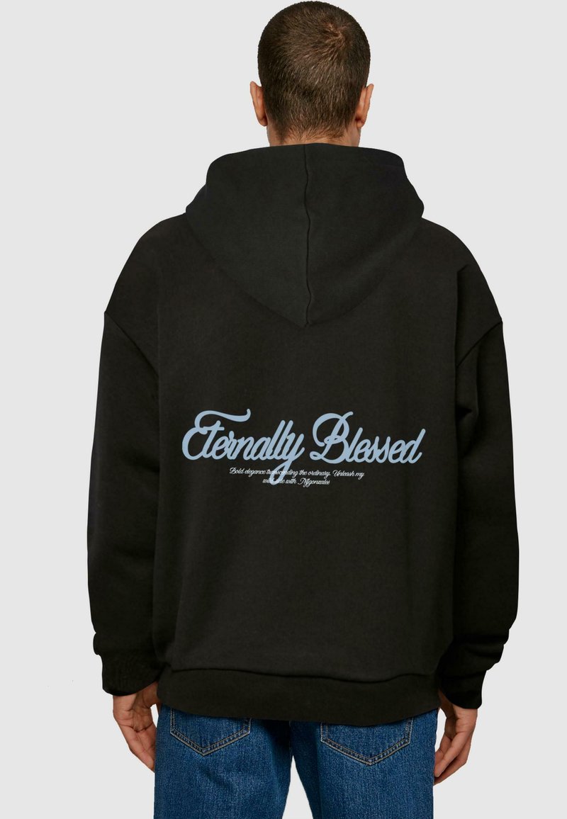 Svart oversized hettegenser med snøring i hetten, med lys blå grafisk tekst på baksiden som sier "Eternally Blessed."