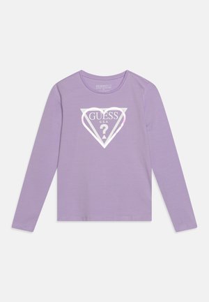 Lilla langærmet skjorte med et hvidt hjerteformet Guess-logo og et spørgsmålstegn i midten foran.