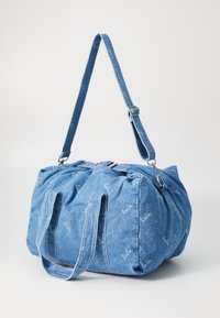 Τσάντα από τζιν σε χαλαρή σχήμα, διαθέτει διπλούς επάνω λαβές, αποσπώμενος ιμάντας για τον ώμο και διακριτό λευκό μοτίβο λογότυπου σε όλη την επιφάνεια.