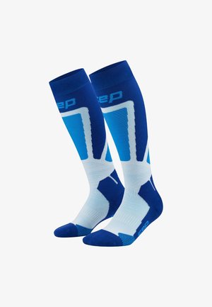 Calze a compressione blu e bianche, con un design a gradiente, maglia testurizzata e punte rinforzate. Logo visibile vicino al bordo superiore.