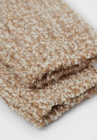 Chunky strikket tørklæde i en blanding af beige og cremefarver, med et struktureret mønster af bløde fibre og et løst vævet design.