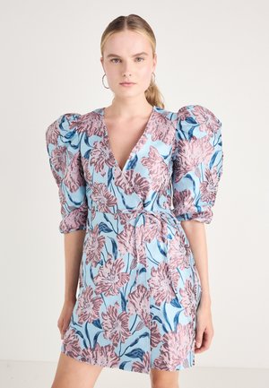 Bloemrijke wikkeljurk met pofmouwen, een diepe V-halslijn en een blauwe achtergrond met roze en blauwe bloemenpatronen.